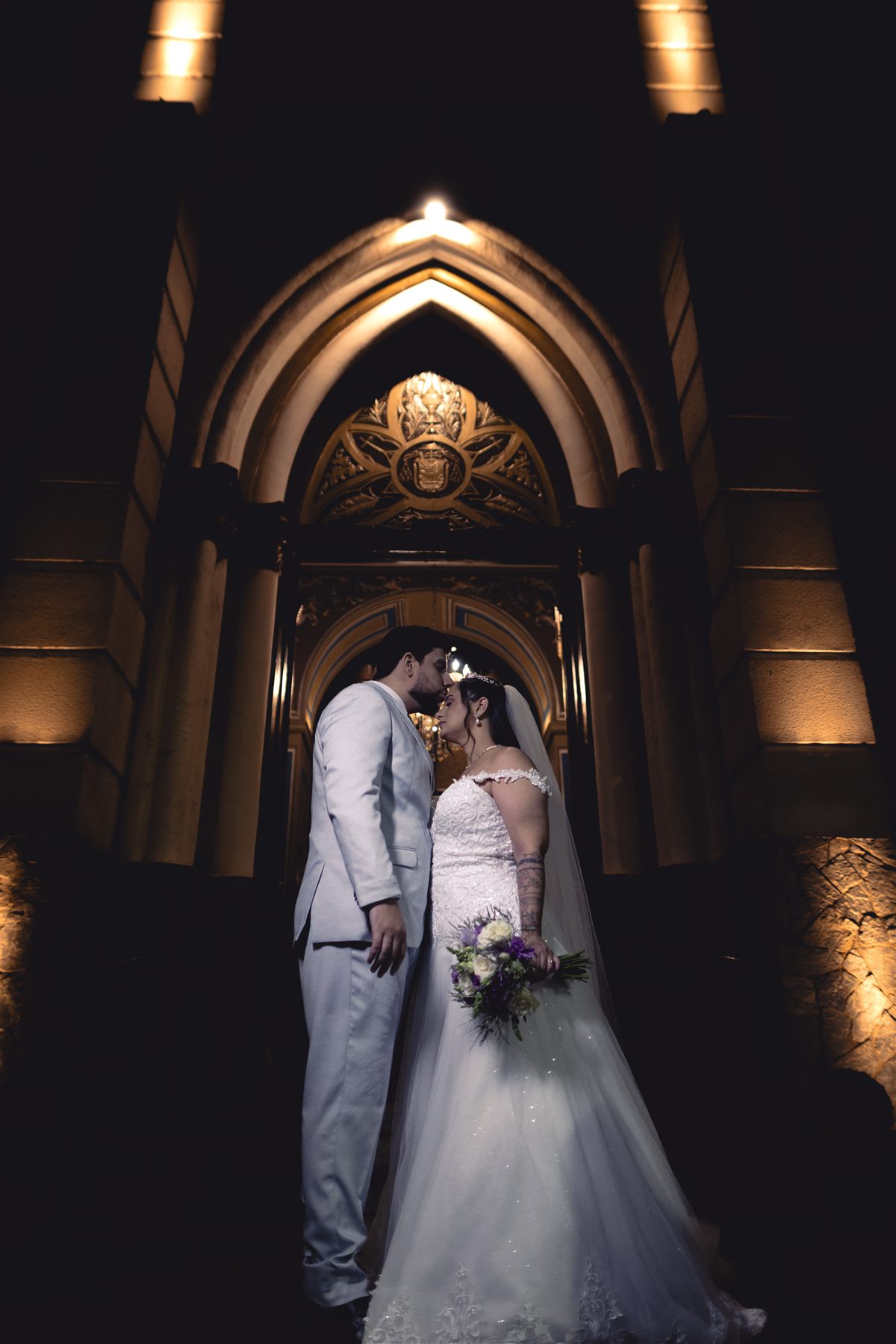 Casal em retrato noturno na entrada da igreja
